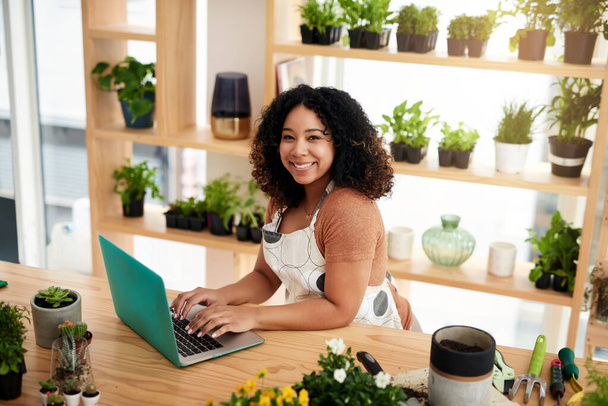 Laptop, portrait and plant with woman in small business for planning, networking and website. Entrepreneurship, startup and technology with African female botanist for nature, green and garden shop. - Photo, Image