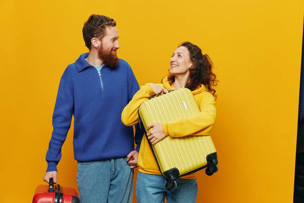 Žena a muž se usmívá, kufry v ruce se žlutým a červeným kufříkem vesele se usmívá a křivě, žluté pozadí, na výlet, rodinná dovolená výlet, novomanželé. Kvalitní fotografie - Fotografie, Obrázek