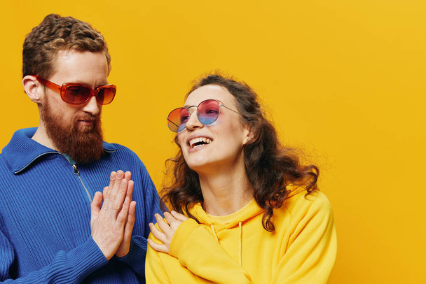 Чоловік і жінка посміхаються весело і криві окуляри, на жовтому тлі, символи знаки і жести рук, сімейна стрілянина, молодята. Високоякісна фотографія - Фото, зображення
