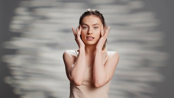 Beauty model using moisturizing face cream for skincare routine, creating ad campaign for natural products. Happy flawless woman posing on camera to promote nourishing uplifting look. - Valokuva, kuva