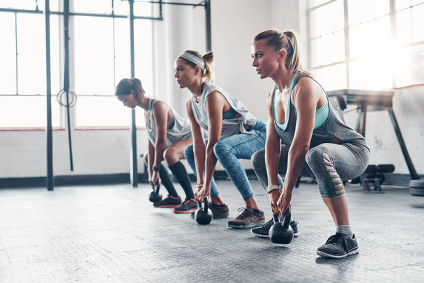 Kettlebell, training and women with workout, exercise and performance for wellness, healthy lifestyle or self care. Female athletes, friends or group with gym equipment, sports and stretching routine. - Photo, Image
