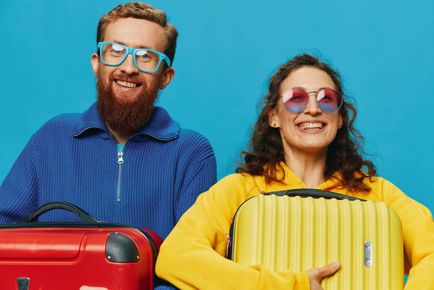 Frau und Mann lächeln Koffer in der Hand mit gelben und roten Koffer Lächeln Spaß, auf blauem Hintergrund, packen für eine Reise, Familienurlaub Reise. Hochwertiges Foto - Foto, Bild