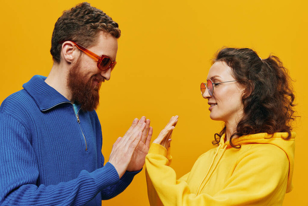 Homem e mulher casal sorrindo alegremente e torto com óculos, no fundo amarelo, símbolos sinais e gestos de mão, tiro em família, recém-casados. Foto de alta qualidade - Foto, Imagem
