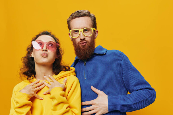 Mann und Frau lächeln fröhlich und schief mit Brille, auf gelbem Hintergrund, Symbolen und Handgesten, Familienshooting, Brautpaar. Hochwertiges Foto - Foto, Bild