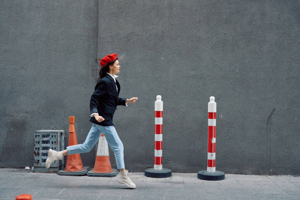 Mulher de moda correndo pela rua em frente ao turista da cidade em roupas elegantes com lábios vermelhos e boina vermelha, viagens, cor cinematográfica, estilo vintage retro. Foto de alta qualidade - Foto, Imagem