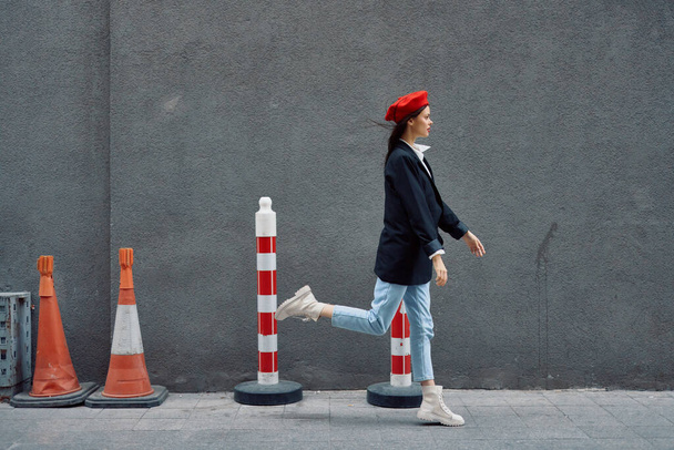 Modefrau läuft die Straße hinunter vor dem Stadttouristen in stilvoller Kleidung mit roten Lippen und roter Baskenmütze, Reise, Filmfarbe, Retro-Vintage-Stil, spät zur Arbeit, laufen. Hochwertiges Foto - Foto, Bild