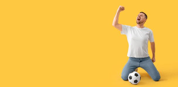 Sarı arka planda futbol topu ve mesaj için yeri olan mutlu çığlık atan adam. - Fotoğraf, Görsel