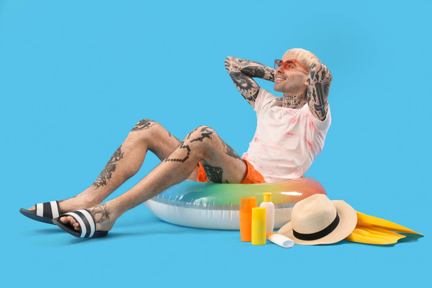 Tattooed man with beach accessories on light blue background - Фото, зображення