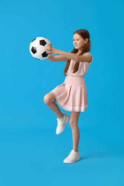 Маленька дівчинка з футбольним м'ячем на синьому фоні
 - Фото, зображення
