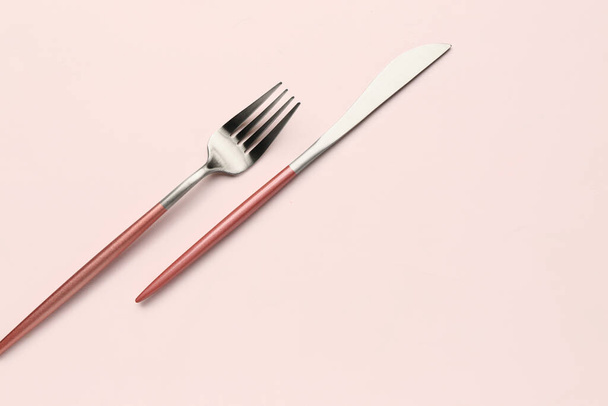 Stainless steel fork and knife with pink handles on white background - 写真・画像