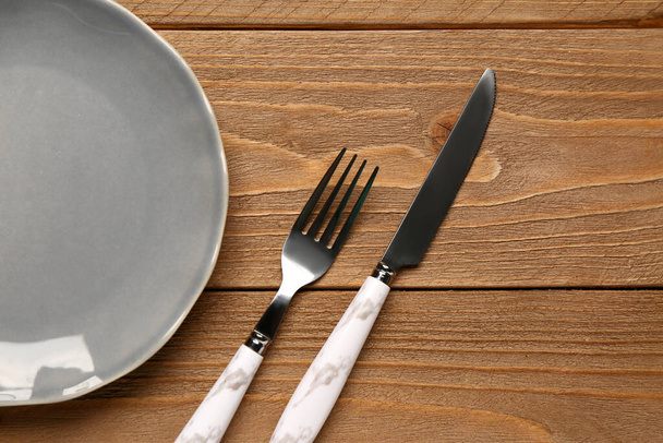 Plaque avec fourchette et couteau en acier inoxydable sur fond en bois - Photo, image
