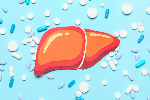 Orange paper liver with pills on blue background - Фото, изображение
