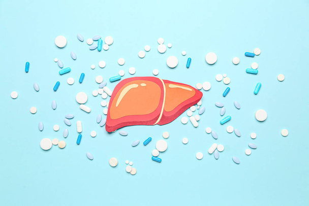 Orange paper liver with pills on blue background - Foto, Imagem