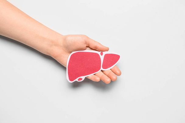 Hígado de papel rojo con la mano femenina sobre fondo gris - Foto, Imagen