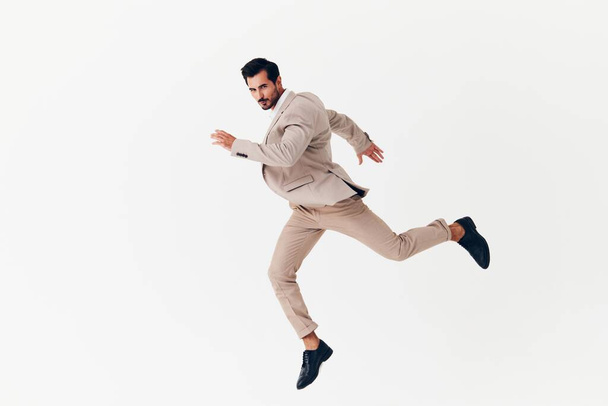Takım elbiseli adam gülümseyen profesyonel koşu yapan erkek işadamı bej arka plan kravatı çekici mutlu ofis ayakta zafer kazanan iş başarısı fikri - Fotoğraf, Görsel
