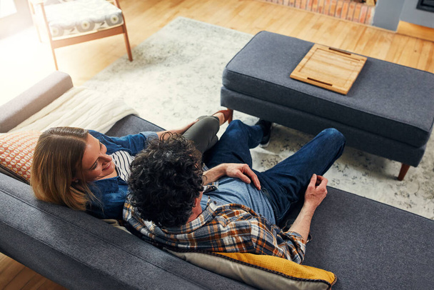 Top view, happy couple and relax on couch in home for quality time, love and care of conversation, discussion and support. Man, woman and talking on sofa for break, bonding and happiness together. - Fotoğraf, Görsel