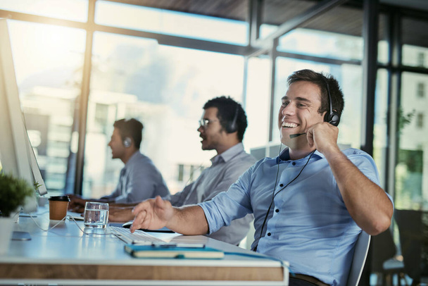 Call center, customer care or service and a man consultant laughing for funny support or assistance on the phone. Smile, crm and contact us with happy male telemarketing agent in his office for help. - Valokuva, kuva