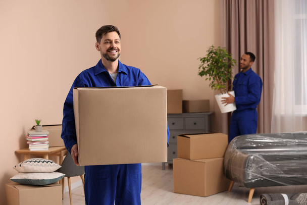 Male movers with cardboard boxes in new house - Foto, Imagem
