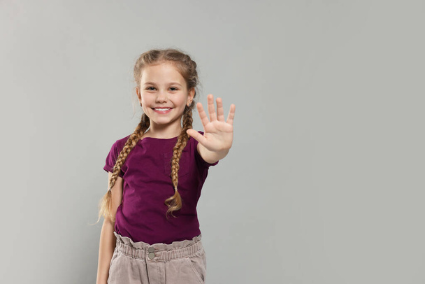 Happy girl giving high five on light grey background, space for text - Foto, immagini