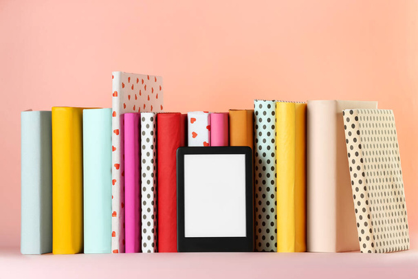 Modern e-book reader and hard cover books on pink background - Fotografie, Obrázek