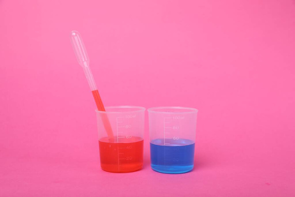 Beakers with colorful liquids on bright pink background. Kids chemical experiment set - Foto, afbeelding
