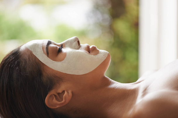 Feeling relaxed and calm. a young woman lying on a spa table with a face mask on - Photo, Image