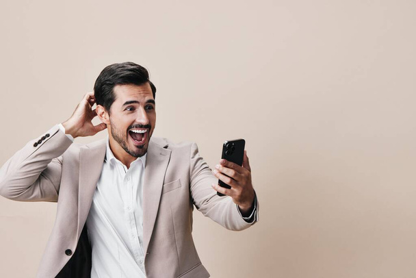 άνθρωπος νεαρός τηλέφωνο κοστούμι γκρι smartphone κρατήσει πορτρέτο lifestyle απομονωμένη τεχνολογία χαμόγελο τηλέφωνο κλήση blogger κινητό κύτταρο κυβερνοχώρο αυτοπεποίθηση χαρούμενος επιχειρηματίας - Φωτογραφία, εικόνα