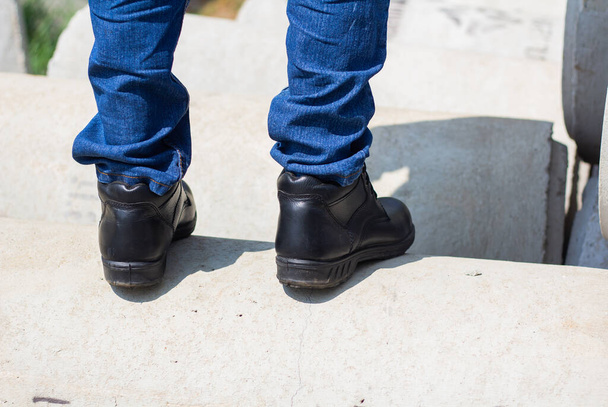 Viseljen biztonsági cipőt a munkahelyi biztonság érdekében. az építőmunkások biztonsági cipőt viselnek. Gyári biztonsági koncepciójú emberek - Fotó, kép