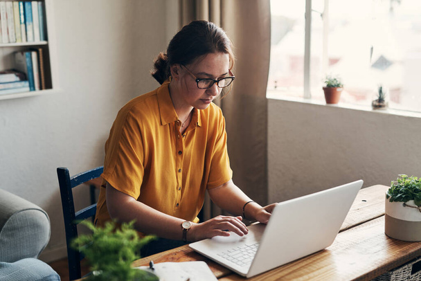 Острый фокус выполняет любую задачу. молодая женщина, использующая ноутбук, работая из дома - Фото, изображение