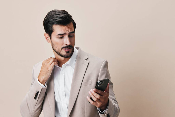 man connection smile smartphone call young phone online beige cellphone suit business portrait handsome happy technology hold internet trading background adult - Photo, Image