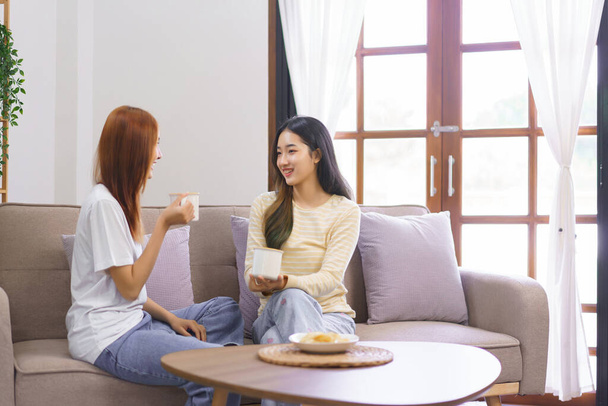 Aktivität zu Hause, LGBT-Lesben sitzen auf der Couch und trinken Kaffee, während sie miteinander reden. - Foto, Bild