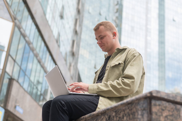 Sad guy with hearing aid using laptop outdoors - Zdjęcie, obraz