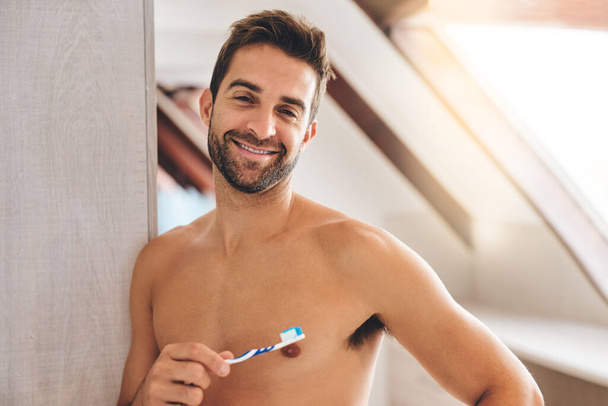 Muotokuva, paidaton ja onnellinen mies harjaamalla hampaat kylpyhuoneessa hampaiden hyvinvointi, terve hymy ja kehon huolellisesti kotona. Seksikäs kaveri, hammasharja ja suullinen puhdistus raikkaaseen hengitykseen ja aamuhygieniaan. - Valokuva, kuva