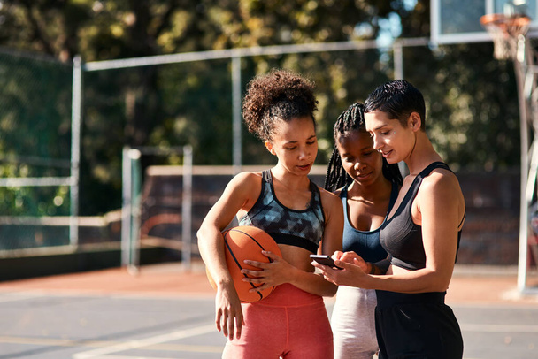 I have to show you all something. a diverse group of sportswomen standing together after playing basketball and looking at a cellphone - Foto, Bild