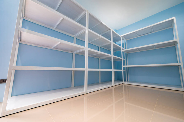 Empty white shelves in blue storage room, Thailand. - Foto, imagen
