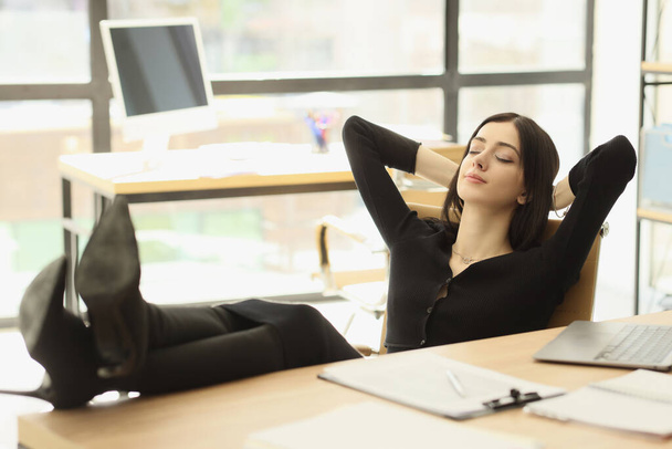 Rahat bayan ofis çalışanı iş yerinde dinlenirken ayaklarını masaya koyuyor. Genç mutlu iş kadını masasında dinleniyor. Ürkütücü iş adamı. - Fotoğraf, Görsel
