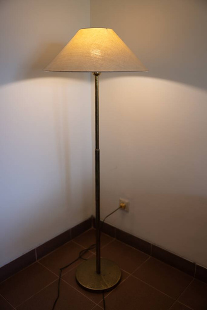 Интерьер с напольной лампой и светящейся лампочкой в темноте ночью, одна лампа в углу у стены напольной лампы. Высокое качество фото - Фото, изображение