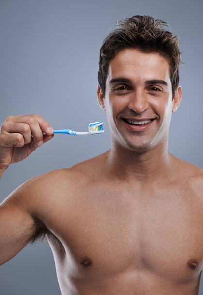 Hes got a picture perfect smile. A smiling young man ready to brush his teeth - 写真・画像