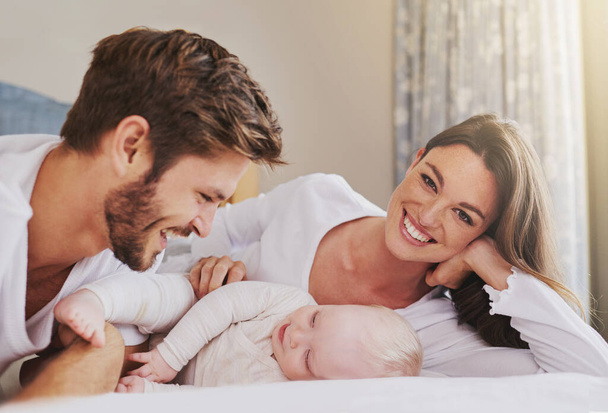 Portrait of happy mother, father and baby in bedroom for love, care and quality time to relax together in house. Mom, dad and smile with cute infant kid for happiness, support and newborn development. - Foto, immagini