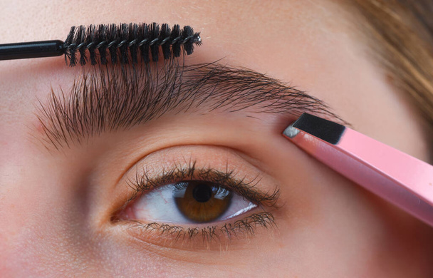 Perfect eyebrows. Close up of woman getting eyebrow make-up. Macro applying cosmetics on her eyebrow with brush. Perfect shape of eyebrow, brown eyeshadows and long eyelashes. Correction eyebrows - Fotó, kép
