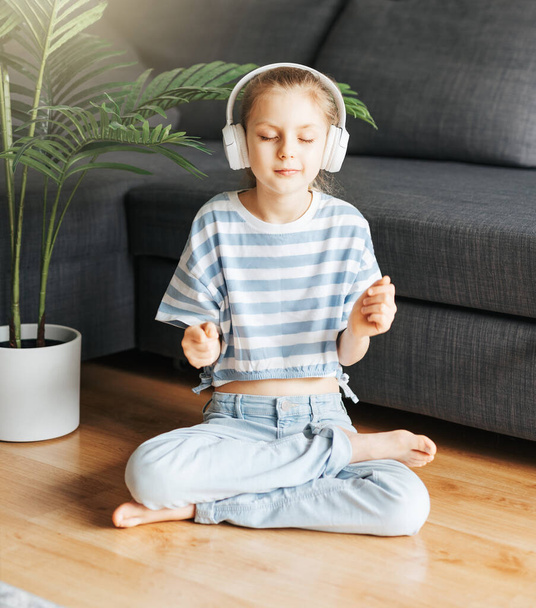 Cute little girl listening to music in headphones  at home. - Zdjęcie, obraz