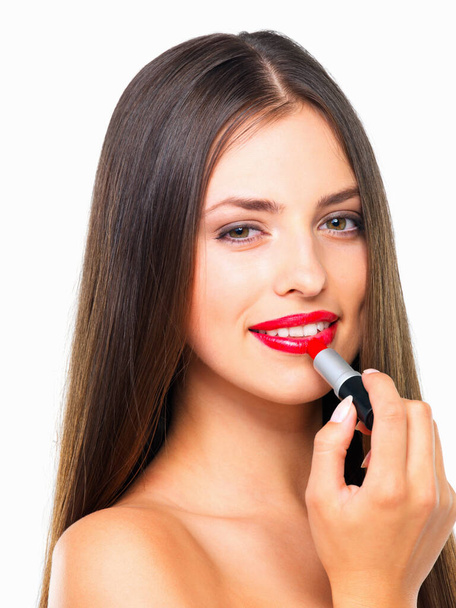 Nothing as classically gorgeous as red lipstick. Studio portrait of a beautiful young woman applying red lipstick against a white background - Foto, afbeelding