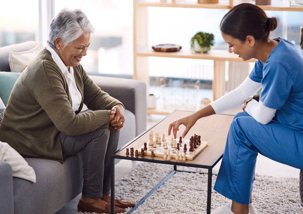 Nők, sakk és nővér egy idős beteggel, idősek otthona és boldogság az egészségügyben. Női személy, egészségügyi szakember és érett hölgy alkalmazottal, ápolás és gondozás játékok és pihenés. - Fotó, kép