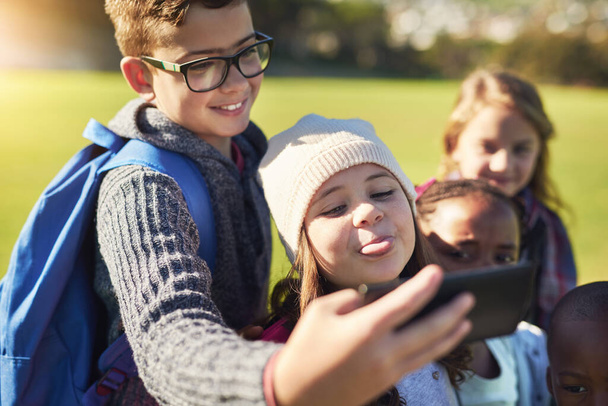 Les enfants de nos jours. un groupe d'élèves du primaire prenant un selfie ensemble sur la pelouse de l'école à l'extérieur - Photo, image