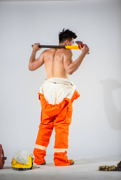 Na čistém bílém pozadí stojí vysoký hasič a věří, že se k němu otočí zády a ukáže svou sílu a odhodlání - Fotografie, Obrázek
