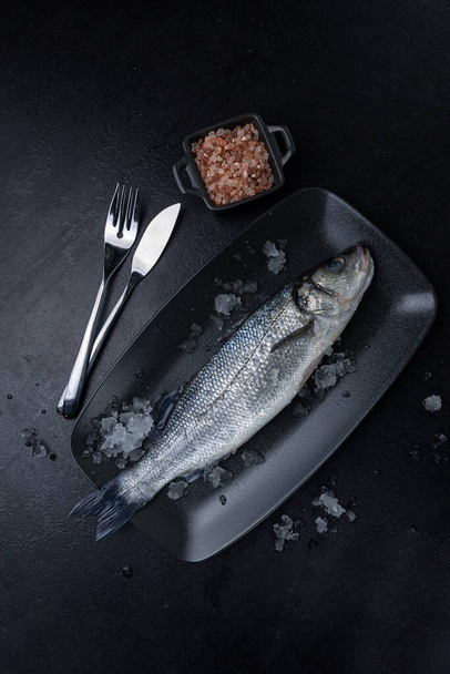raw fish on a black plate - Foto, afbeelding