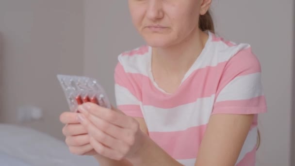 Eine junge Frau nimmt Tabletten gegen Magenschmerzen. Ein monatlicher Frauenzyklus. Schmerzmittel. - Filmmaterial, Video
