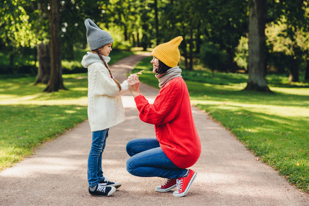 Люди, отношения, отцовство и детство. Мать играет с маленькой дочкой в парке, дарит желтый лист, испытывает эмоции и чувства или любовь к любимой дочери
 - Фото, изображение