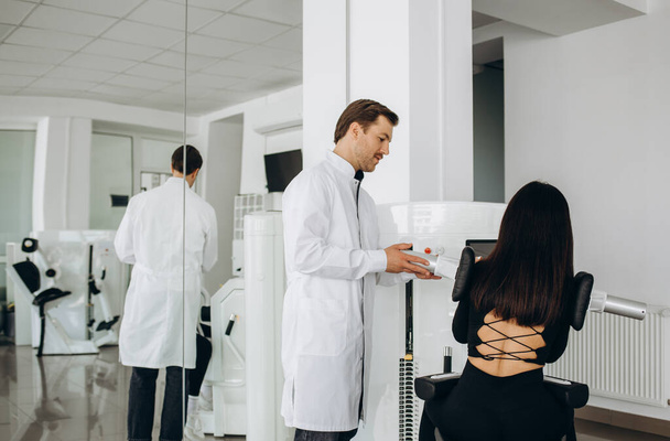 Een vrouw traint met een dokter op simulatoren in een vertebrologische kliniek. - Foto, afbeelding