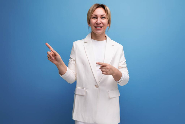 довольно стройная молодая блондинка бизнес-лидер женщина в белой куртке указывая пальцем в сторону. - Фото, изображение